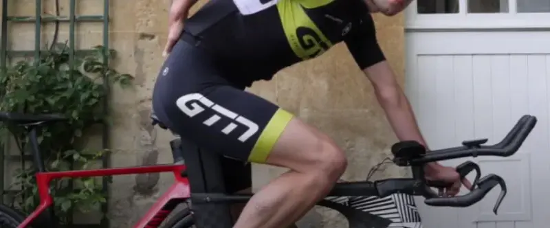 A cyclist holding their lower back in pain during a ride