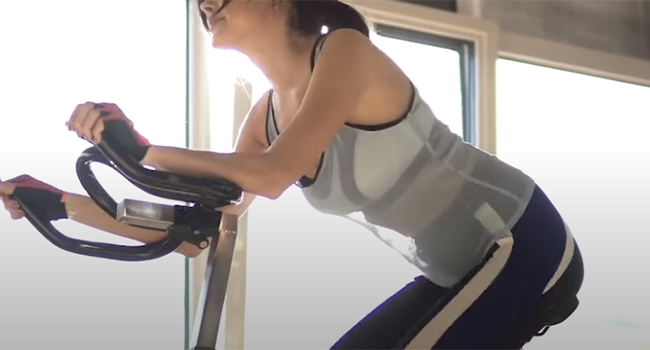 A cyclist standing to climb a hill, engaging the glutes