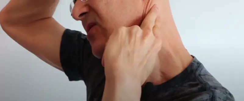 A massage gun targeting a trigger point in the shoulder