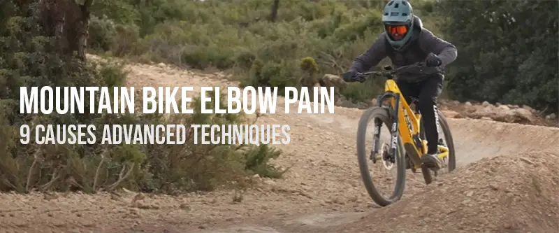 A mountain biker holding their elbow in pain on a trail
