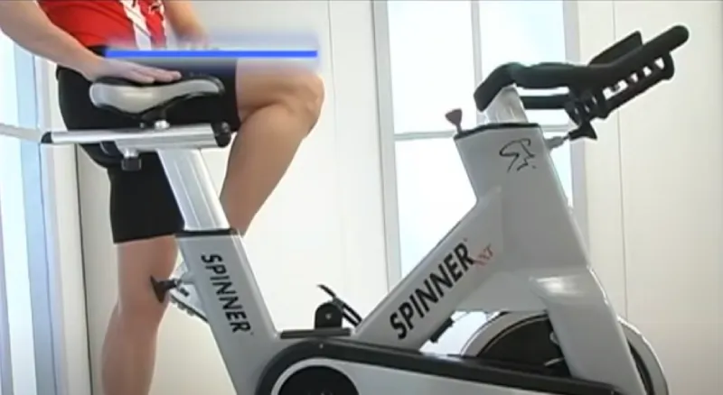 A person with knee bursitis riding a stationary bike