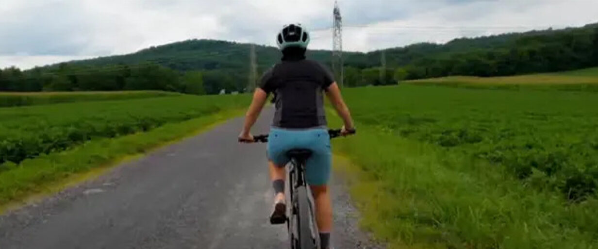 Cyclist adjusting their helmet for a proper, comfortable fit