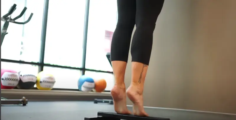 Stretching the calf muscle against a wall post-ride